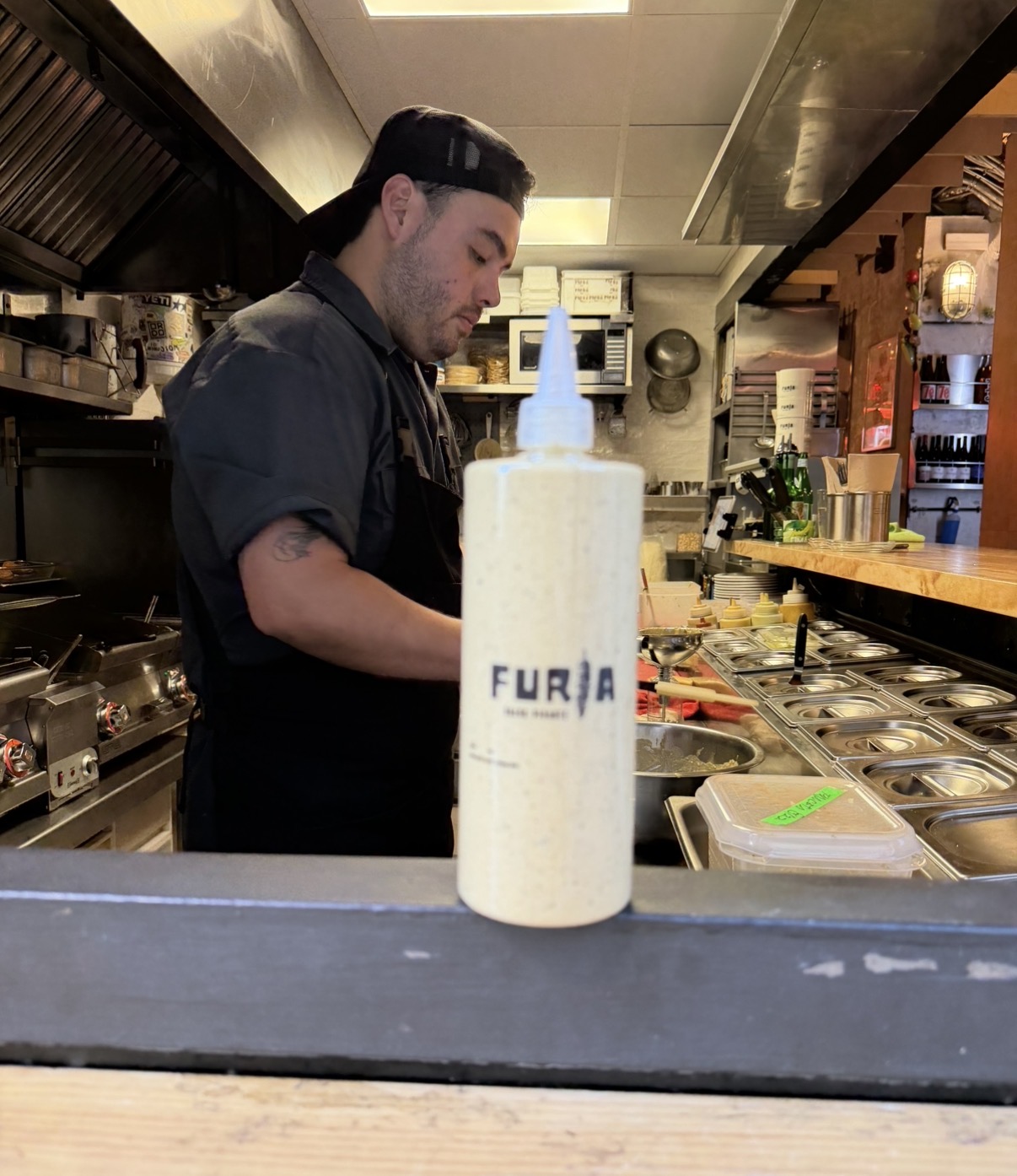 El socio chef junto a la barra con una botella de FURIA
