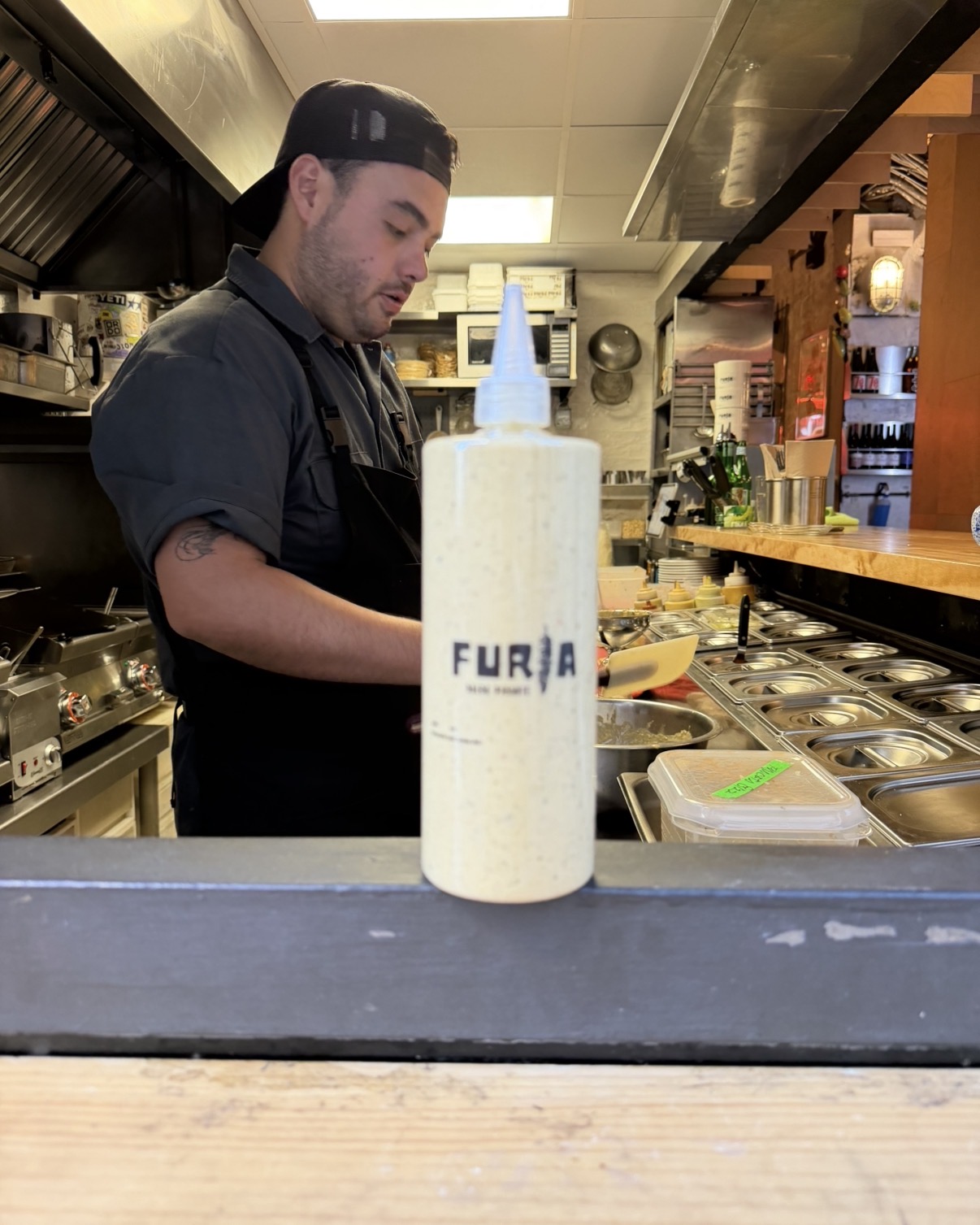 El socio chef junto a la barra con una botella de FURIA