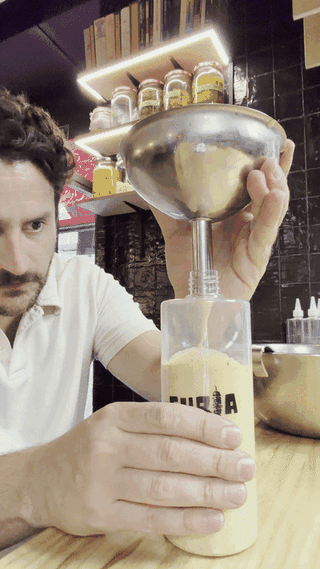 Christian, socio de FURIA, embotellando salsa en la barra